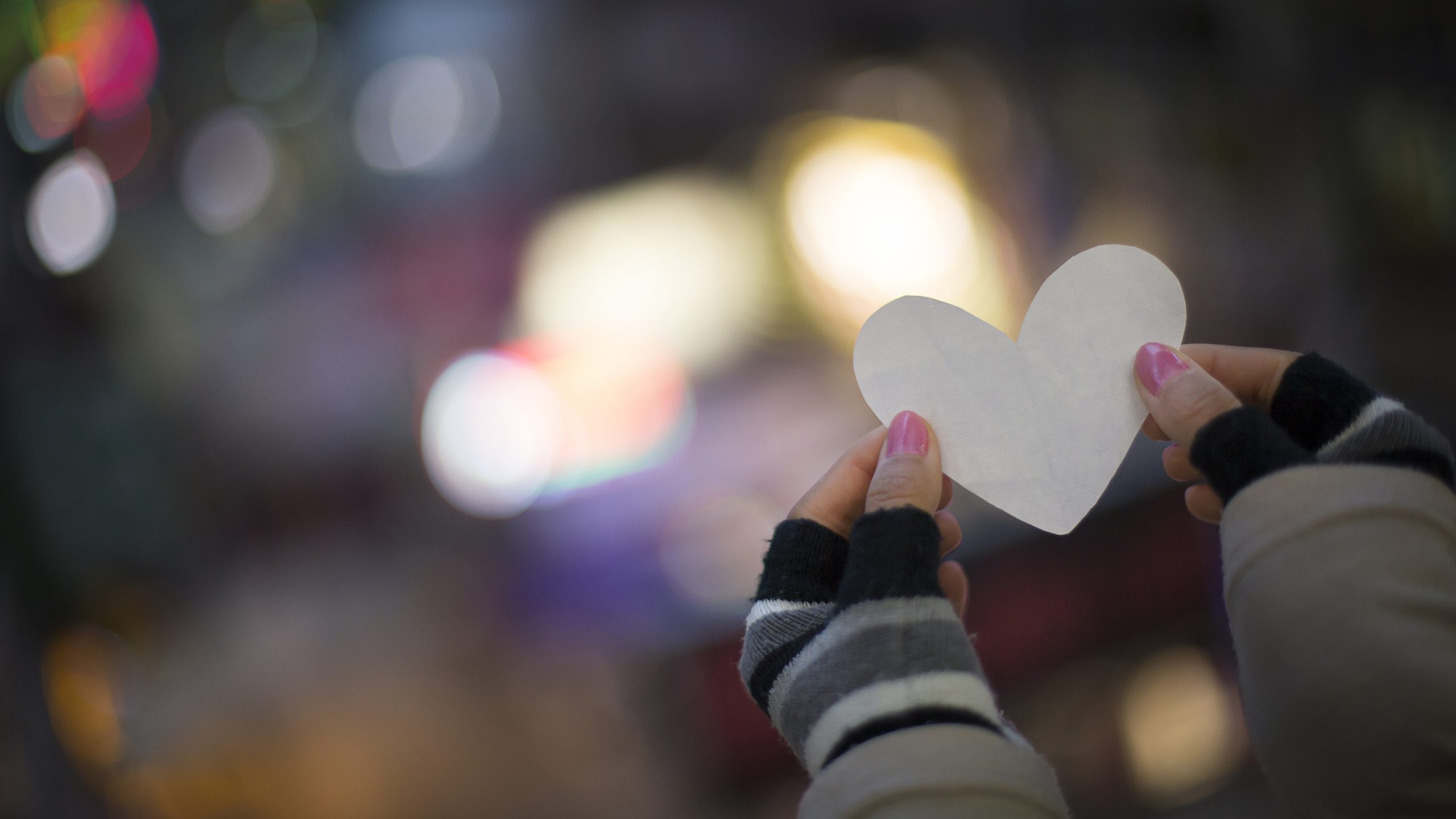 Hands holding a paper heart, blurred background. Photography for a corporate report. Photographer Tuomas Harjumaaskola.