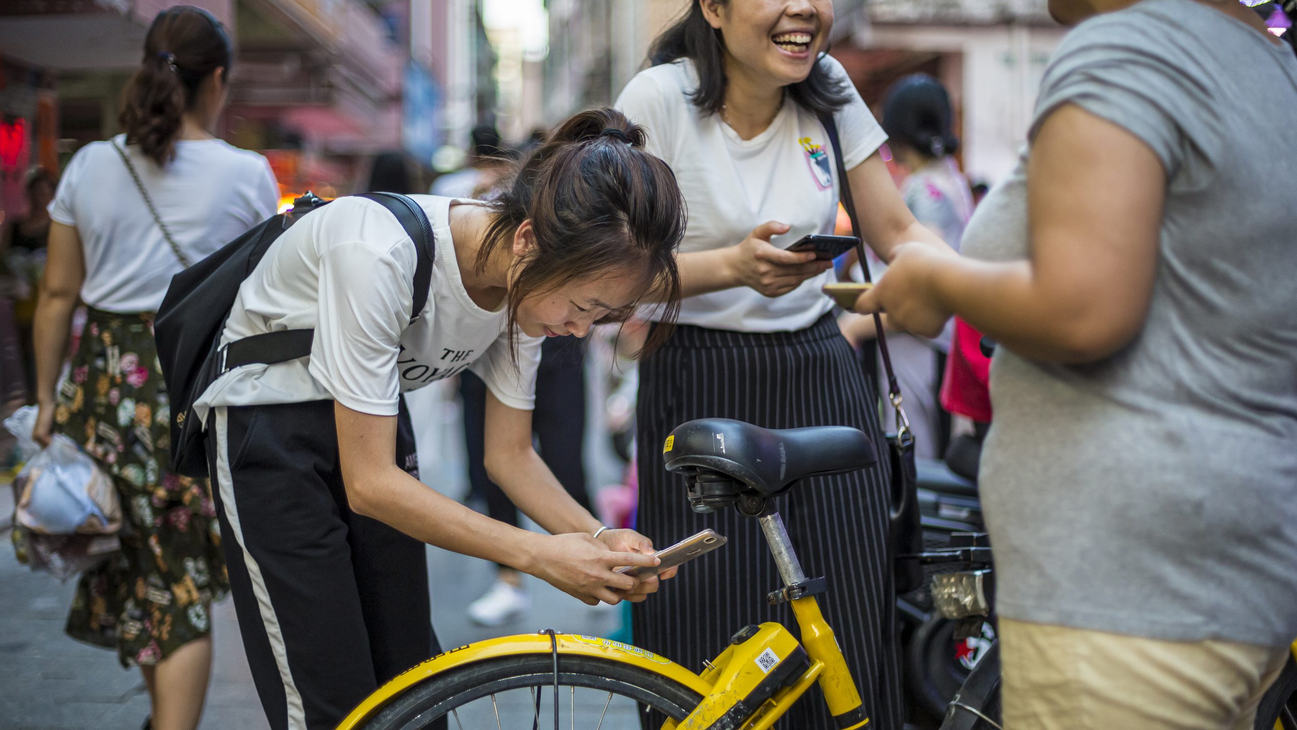 Young women scanning a QR code on a shared bicycle in China - photo by photographer Tuomas Harjumaaskola, China