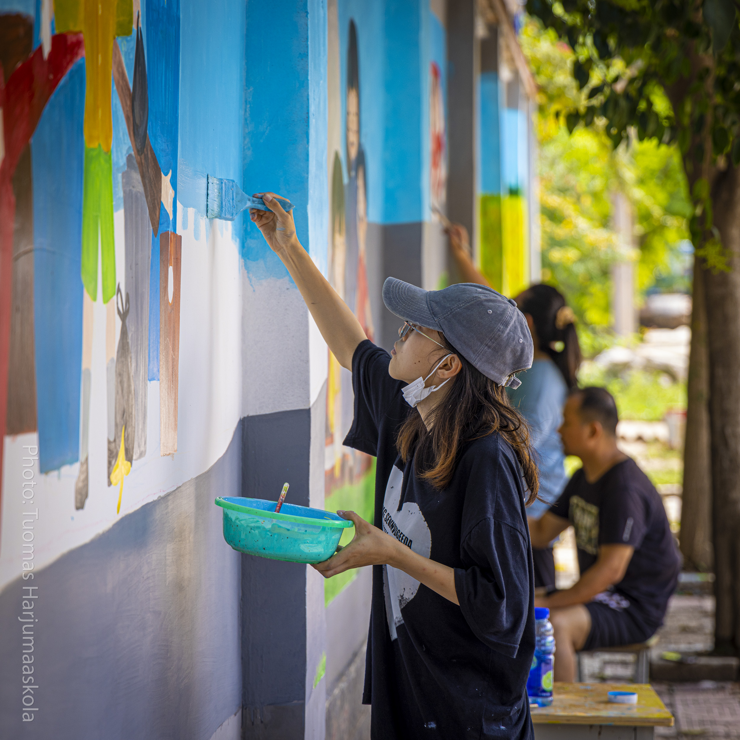 Chinese street artist painting a colorful wall. Photographer Tuomas Harjumaaskola.
