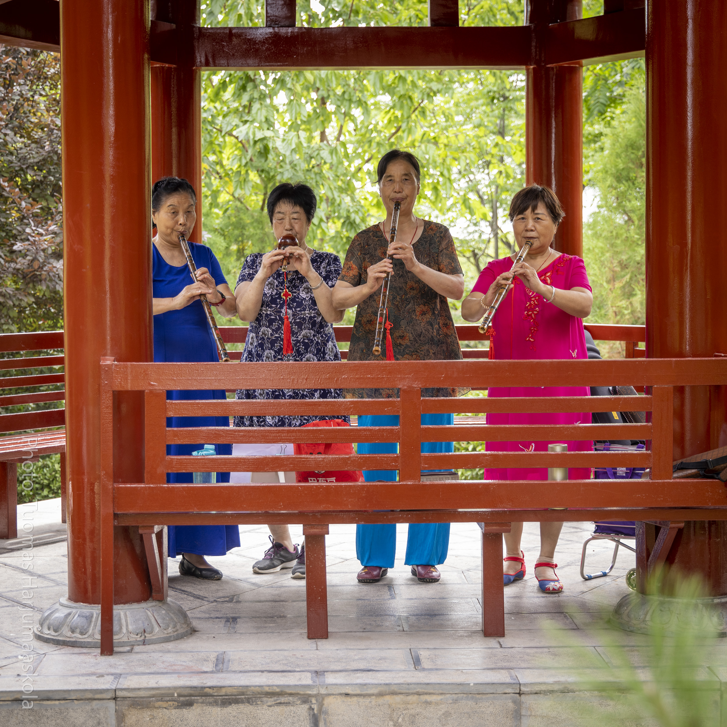A group of Chinese women playing flutes in a pavilion in a park. Photographer Tuomas Harjumaaskola.